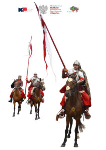 Zdjęcie przedstawia trzech husarzy. Dwaj w rękach dzierżą polskie chorągwie. Ostatni trzyma tarczę. Konie koloru brązowego.