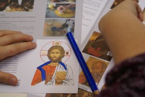 Po lewej i prawej dziecięce dłonie. Po środku kolorowanka z Jezusem Chrystusem.