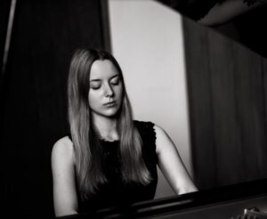 Czarno-białe zdjęcie z młodą kobietą grającą na fortepianie